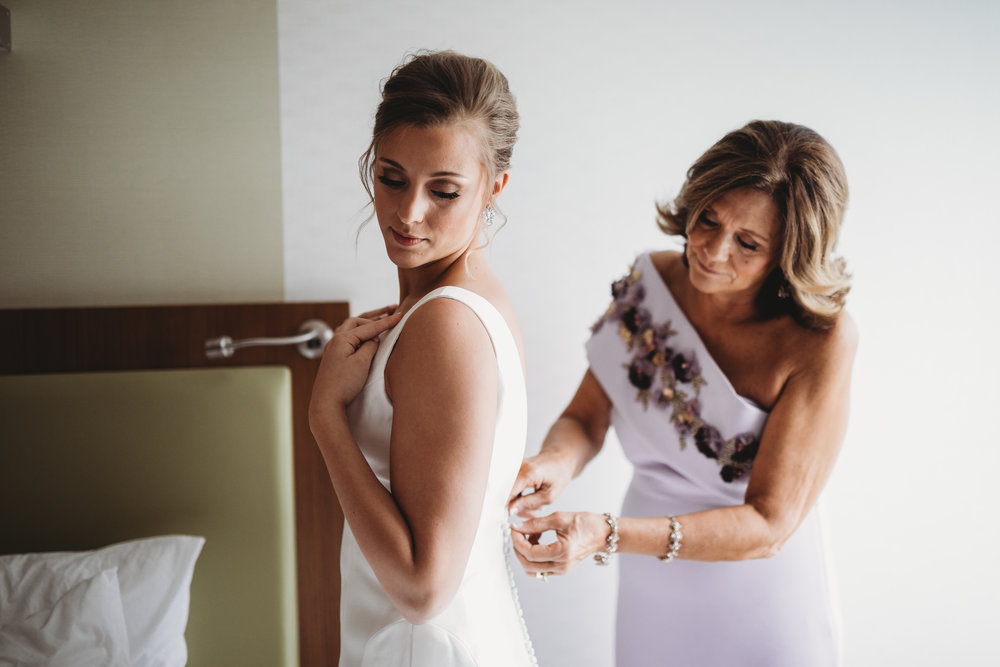 bride-getting-ready-in-hotel-lauren-ashley-studios-putting-on-dress.jpg