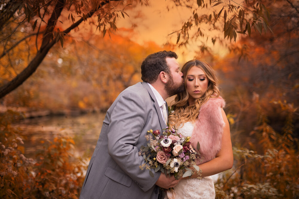 autumn wedding photography groom kisses his bride in fall foliage