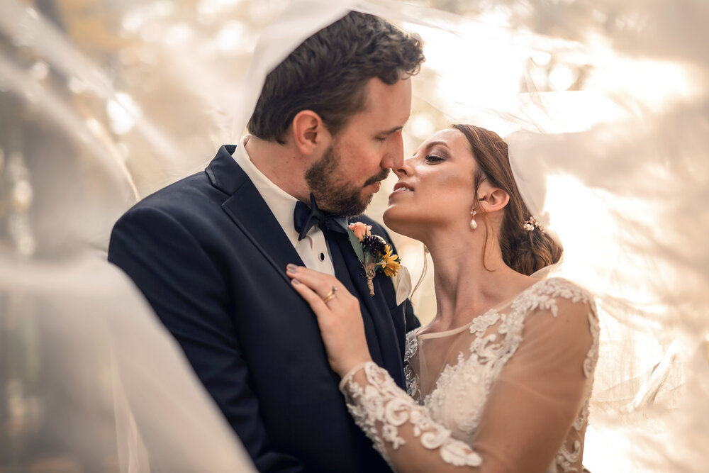 bride and groom kiss beneath of the veil for a wedding photoshoot
