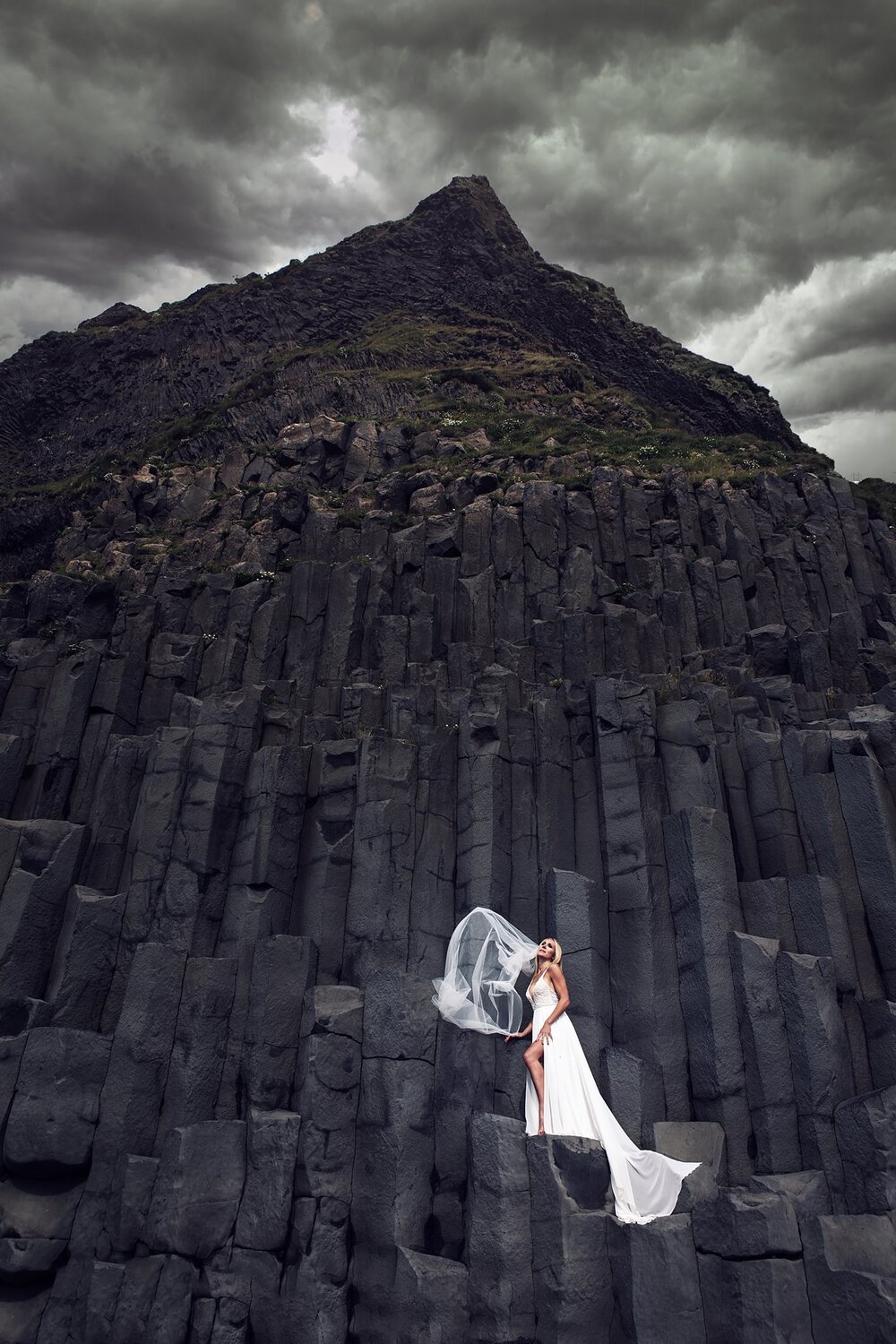 bride on the black cliffs of reynisfjara by iceland destination wedding photographer lauren ashley s