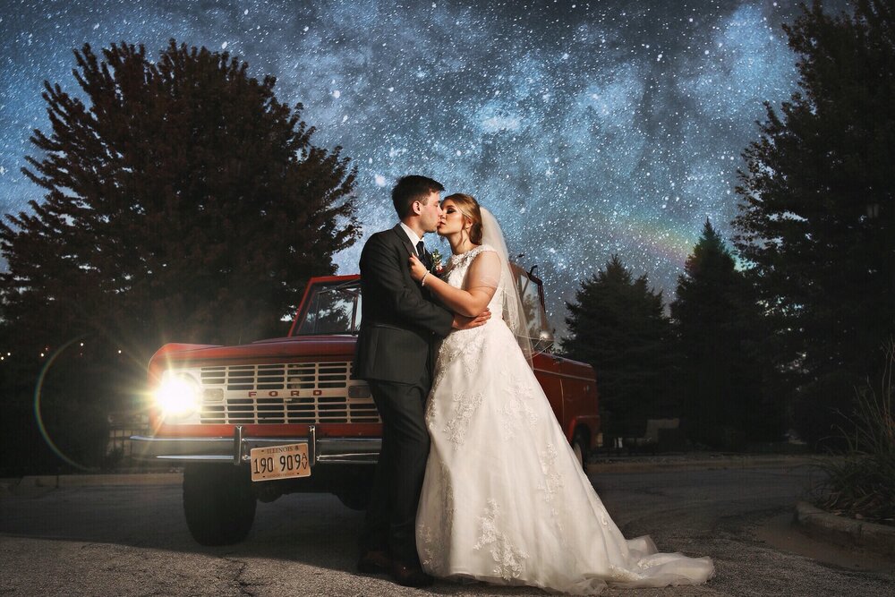 wedding photo of a bride and groom with an old ford bronco beneath a starry sky